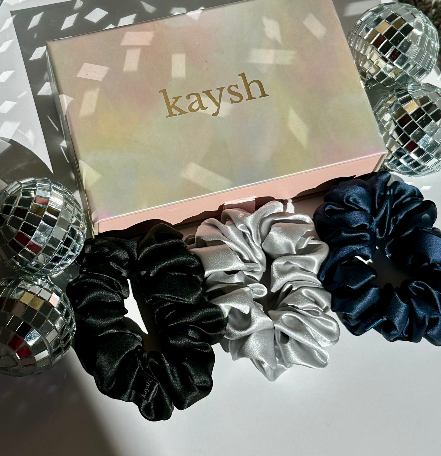 100% mulberry silk scrunchies next to a gift box. Shiny, luxurious and soft to touch. 